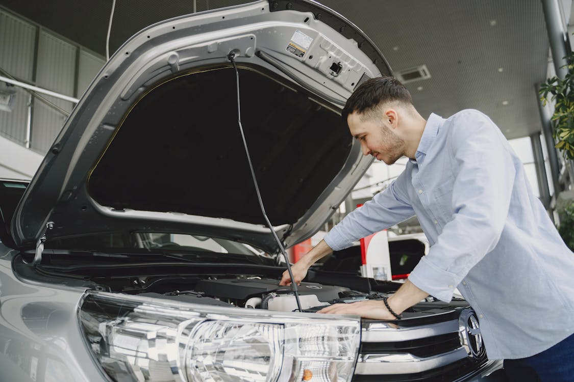 A man inspects the engine of his car, focused on ensuring everything is in proper working order.